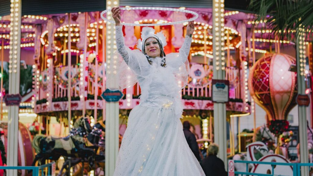 Échassière de la parade blanche jouant avec un cerceau lumineux devant le manège